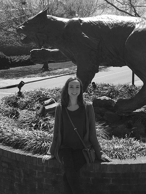 Junior Hallie ORourke sits with a statue of the Davidson College mascot, the wildcat. Visits to colleges such as this one can help students decide where they may want to attend or apply.
