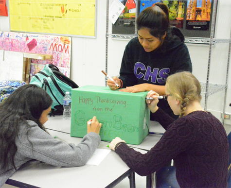 Sophomores Natasha Smith and Tracey Valdez and senior Iva Shuping work together to create a community service box. This box will be filled with Thanksgiving food and given to a family in need. 