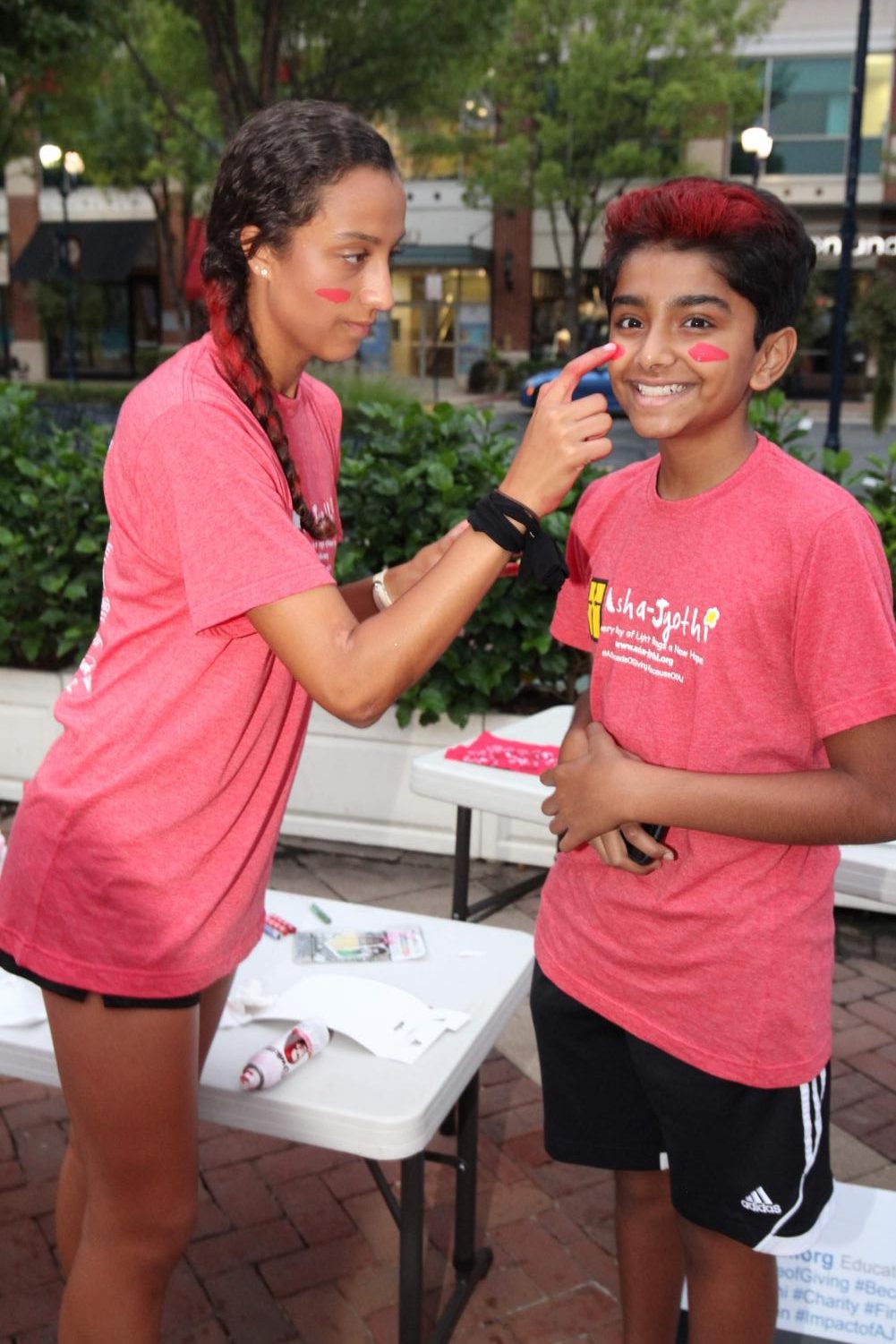 Senior Beka Luebbe and freshman Arjun Rajan prepare for the race by using red face paint and hair spray.