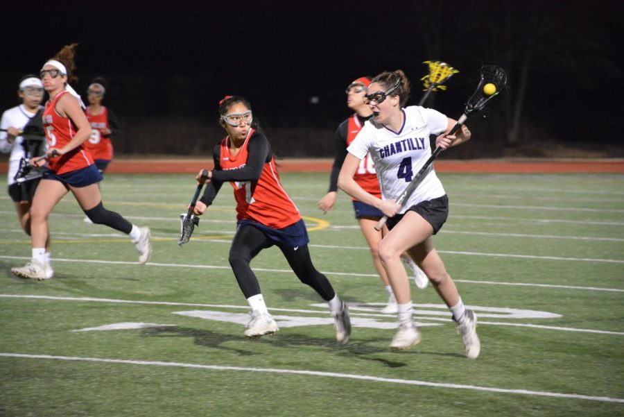 Senior and captain Katie Carita advances the ball down the field during the March 12 home game against Thomas Edison. The team managed its first win of the season, ending the game with a score of 11-2.