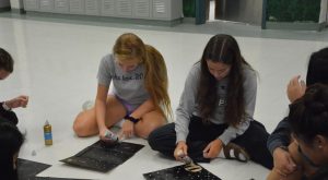 Sophomores Natalie Hogan and Caelin Rowell work on posters for powder puff, a game which takes place during homecoming week. Traditionally, females play football while males cheerlead, but this year the activities are coed.