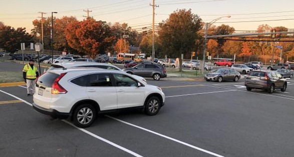 Safety and security assistants P. Jerome and H. Foxwell direct morning traffic in the school parking lot.