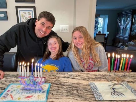 Senior Miranda Schuman with her younger sister and dad lighting their menorahs after the eight nights of Hanukkah.