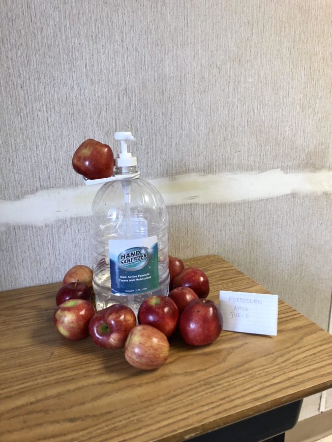 Depicting “forbidden apple juice,” numerous apples surround a hand sanitizer bottle in the modular hallways on Dec. 7.