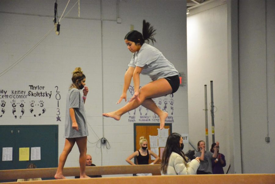 Sophomore Michelle Orantes and sophomore Tanvi Wason practice beam routines on Jan. 25. Orantes works on a wolf jump on the beam.