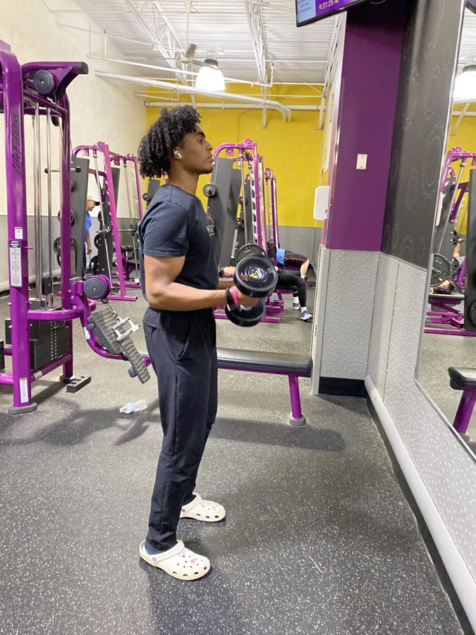 Lifting dumbbells to work on his bicep curl form, junior Karim Sayed finishes his workout routine at Planet Fitness on April 20.