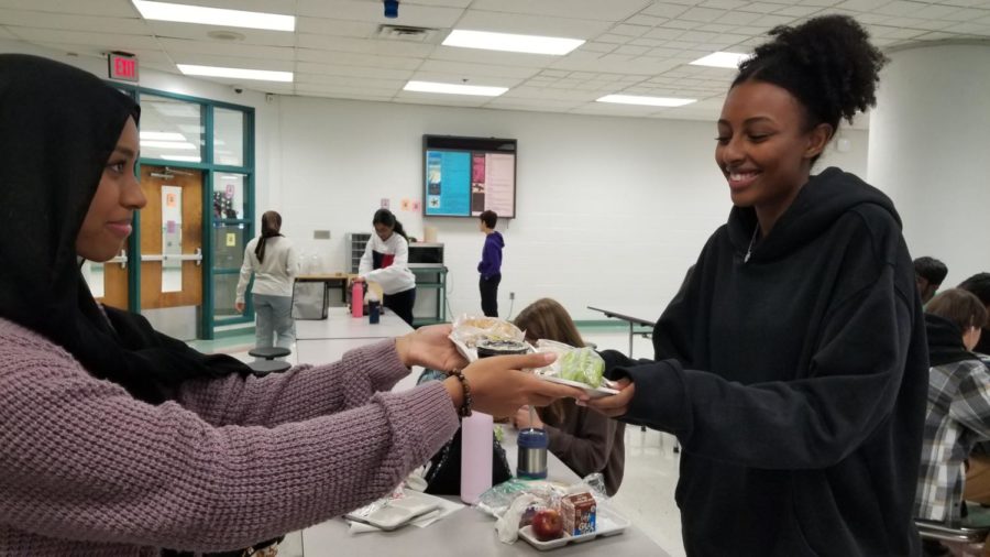 On Oct. 19, Feeding Chantilly president and senior Nebeela Ahmed gives food to senior Sarah Yaregal in the cafeteria as food distribution is a common focus of the club. 