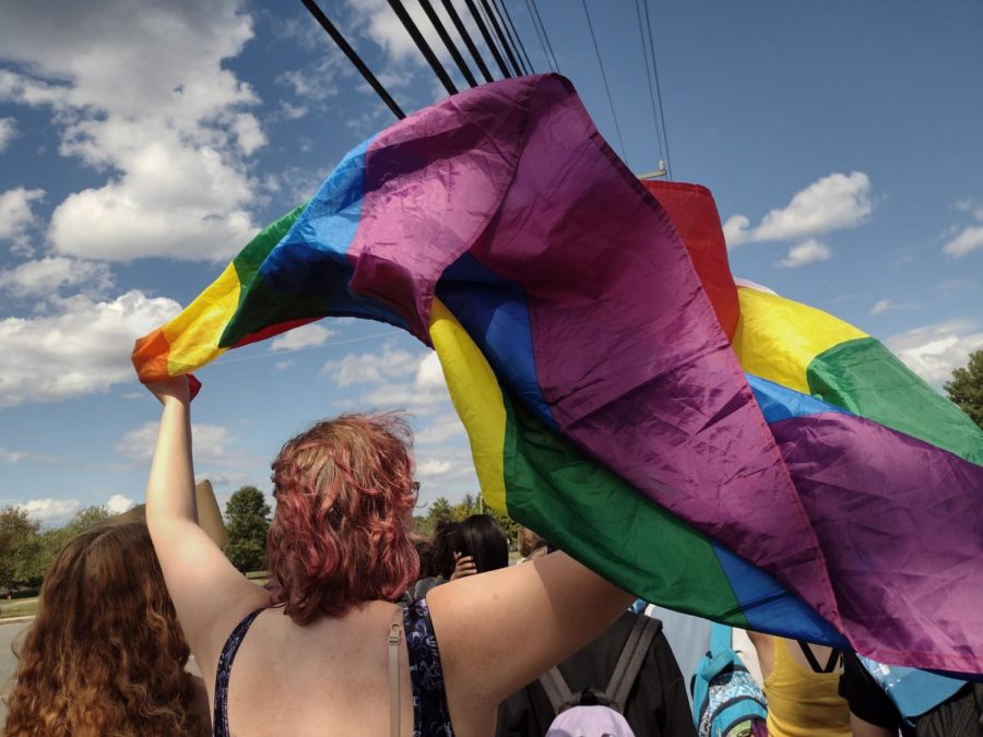 A student waves a pride flag through the air during the walkout on Sept. 27 in protest against the states new model policies.