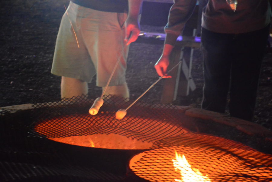 Families come together by the bonfire to savor the traditional winter treat of grilled marshmallows.