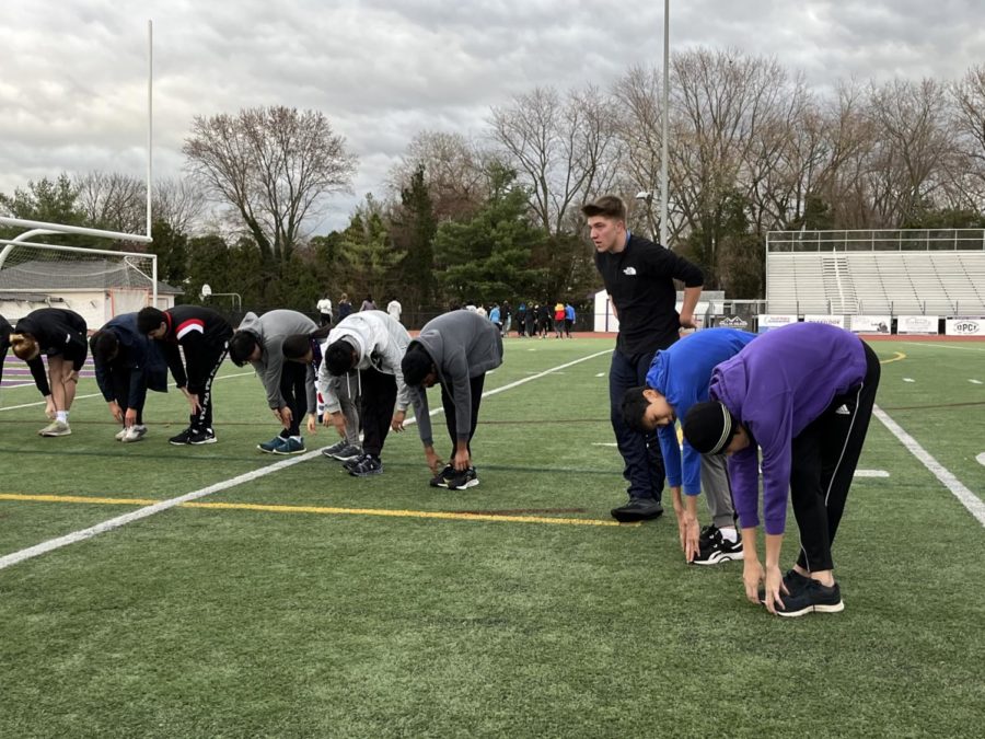 Junior Connor Harrison and members of the winter track and field team stretch at the start of practice on Nov. 30, clad in warm-weather clothes.