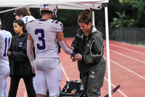 While, athletic trainer and junior Smriti Balasubramanian helps football players during practice on Sept 30, Jake Madaj (#3) gets his hand wrapped by athletic trainer Katelyn Bishop.
