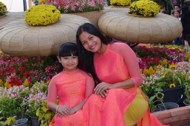 Dressed in a fluorescent colored áo dài, a traditional Vietnamese dress, An Nguyen and her mom celebrate festivities in Vietnam. Áo dài can be worn in less formal settings or during special occasions like Tết, the lunar new year celebration.