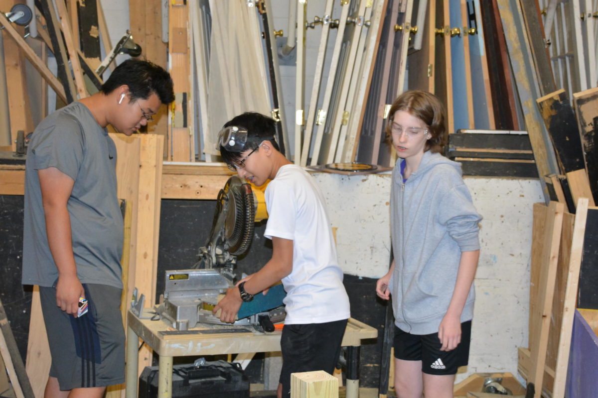 Sophomore+Nathaniel+Huang+and+freshman+Clare+Colburn+use+the+power+saw+to+work+on+construction+while+senior+Sam+Ryu+supervises.+
