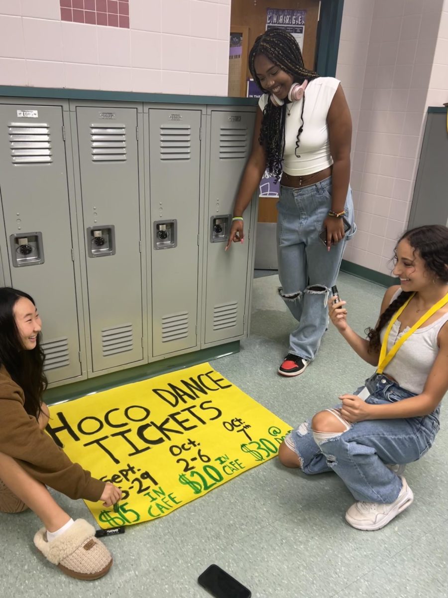 Sophomore Claire Youk and juniors Angel Ndahiriwe and Jenna Abi Joumah add the finishing touches to their Homecoming poster. 