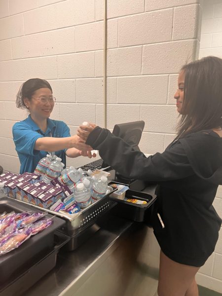 Food service worker Wei Jiang gives Sarah Ali water.
