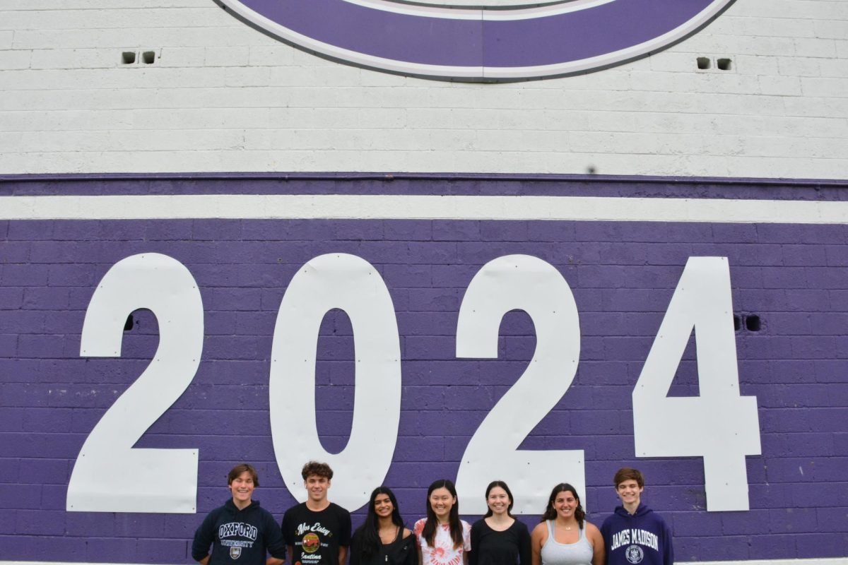 The seniors line up in front of the 2024 sign inside the baseball stadium.