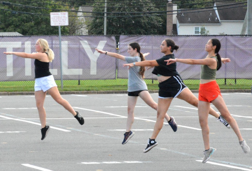 During warmup on Sep. 19, senior captain Mars Barry, senior Stephanie Nicholson, senior Amelia Maurer and junior Hee Theng Chong practice their sautés, which are leaps where the front leg is used to land and the back leg is extended. According to Drum Corps International, practicing dance makes guard members’ skill on equipment even higher because they can move their bodies in an enhanced way. “The hardest part about guard, for me, has always been the dancing,” Barry said. “It’s not really something I’m good at, but I get over it by doing it a bunch and practicing.”