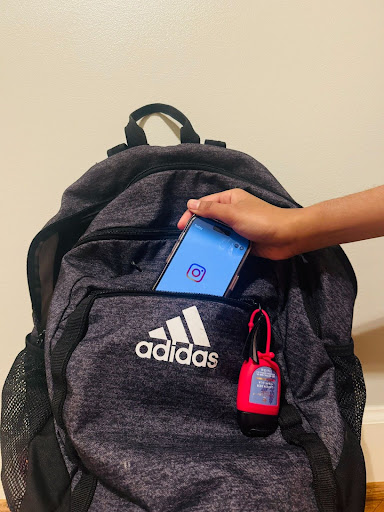 A student slips their phone into their backpack for the rest of the school day. Photo by Varsha Sekar.
