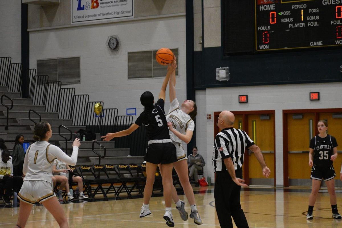 The referee blows the whistle to start the game and both opponents try to swat the ball to their side during jump ball. 