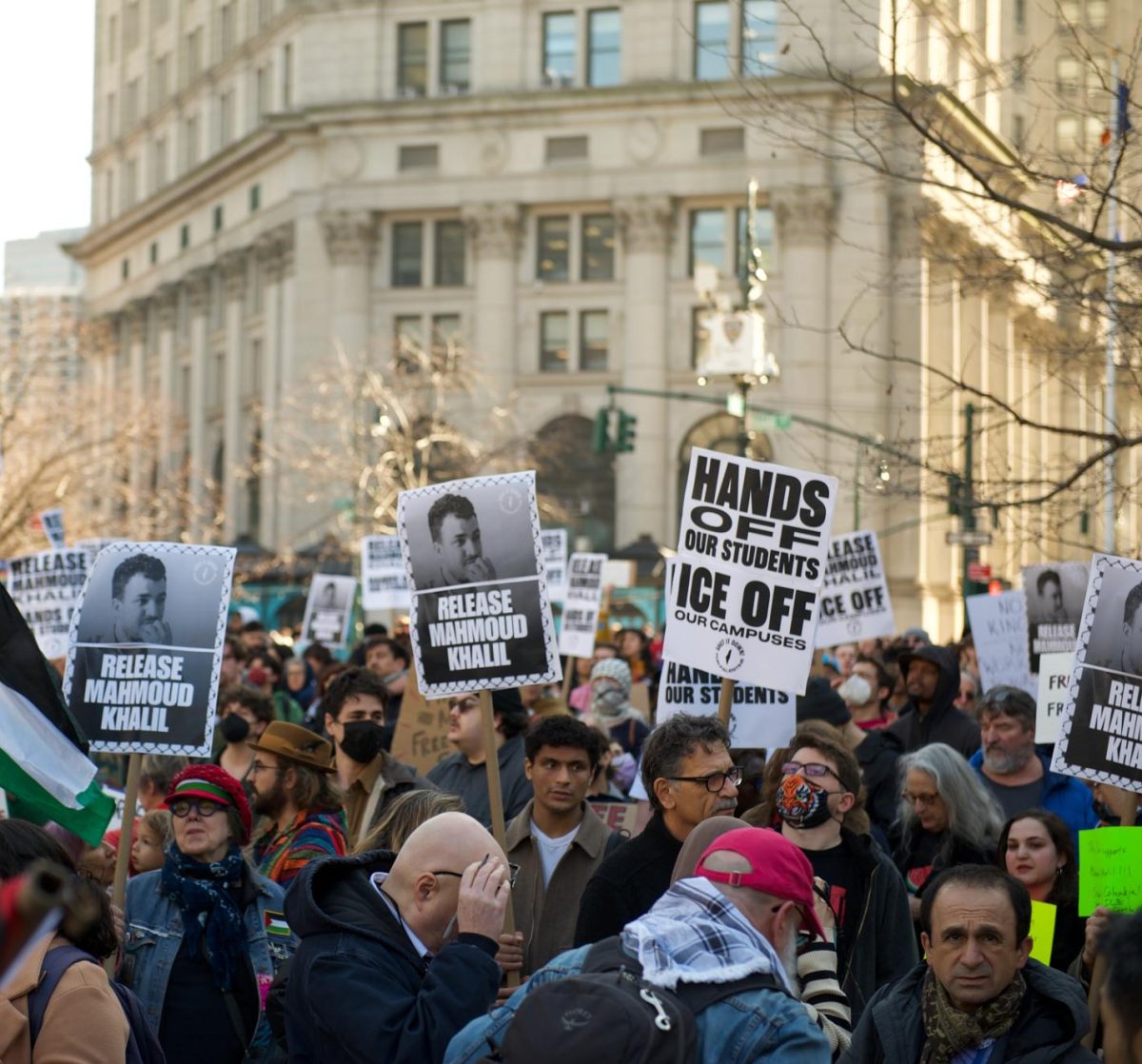 Protesters gather in Thomas Paine Park after the arrest of Columbia University student Mahmoud Khalil by U.S. Immigration and Customs Enforcement. One of the signs reads, “HANDS OFF OUR STUDENTS / ICE OFF OUR CAMPUSES.” Photo by SWinxy. This photo is licensed under the Creative Commons Attribution 4.0 International License. 