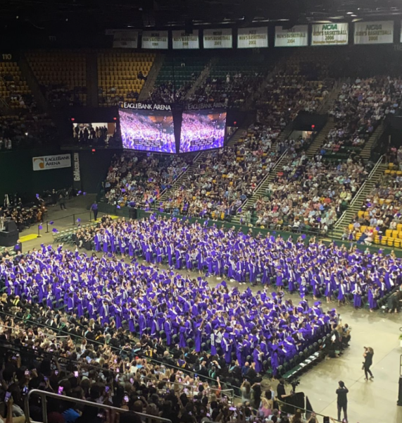 Class of 2024 graduates throw their purple caps in the air, celebrating graduation in EagleBank Arena on June 7, 2024. 
