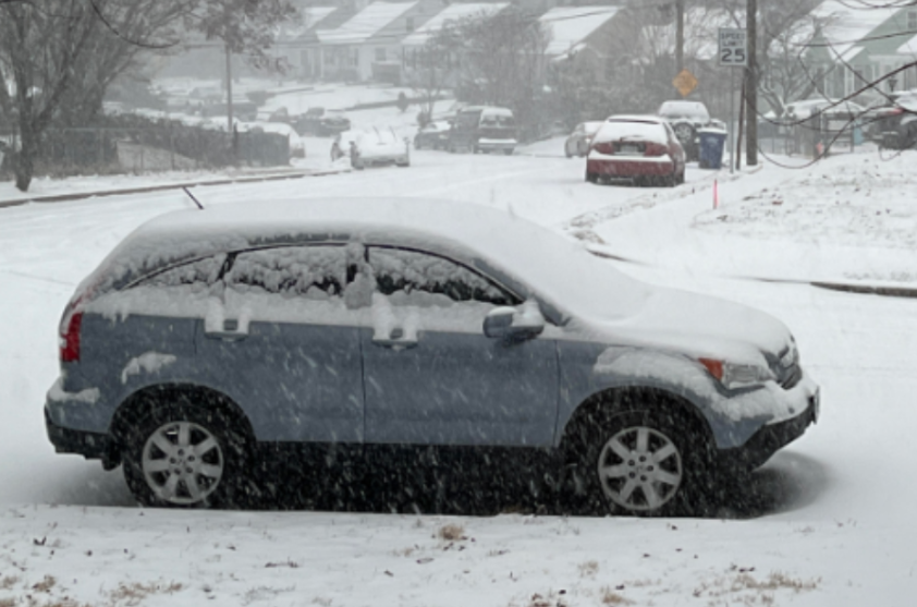 A car covered in snow is parked in Fairfax County on Jan. 16, 2022. According to the Defensive Driving School, when parking in snow and ice, avoid inclines, clear snow around car tires and lift windshield wipers to prevent them from freezing. Photo by Kris Brown. 