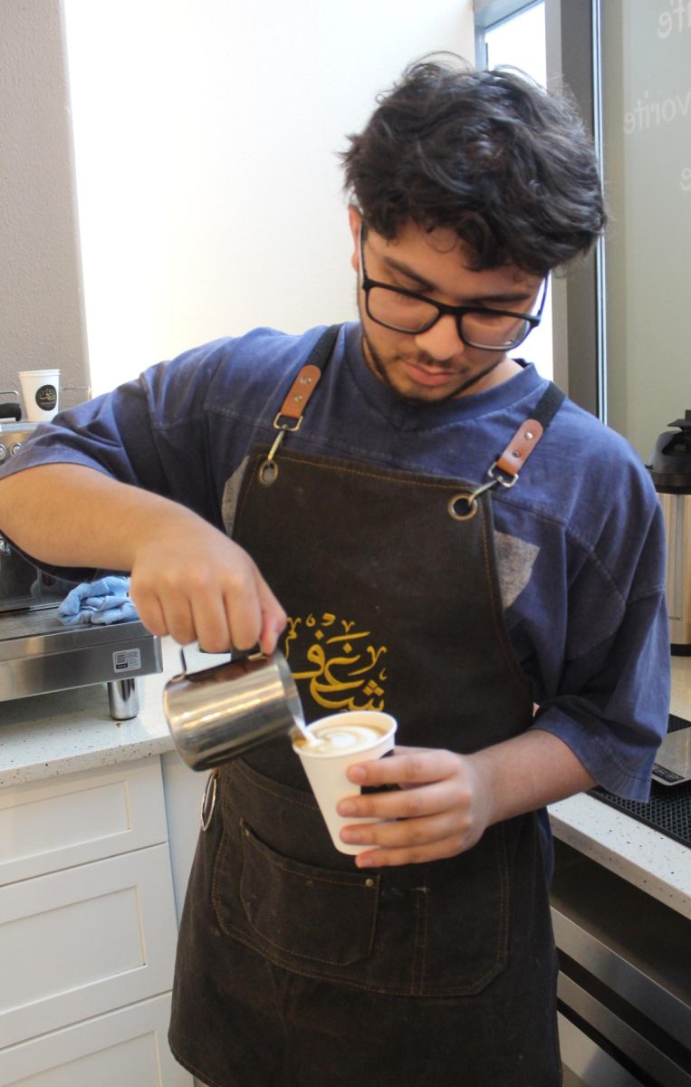 Senior Zain Farid pours milk to create latte art in a cup during his shift on Nov. 30.