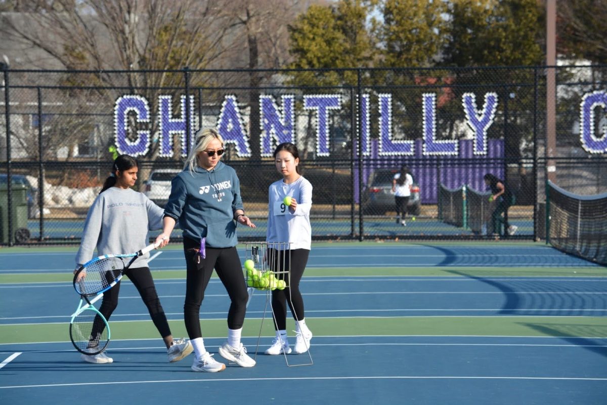 As Coach Alex Kang instructs girls with drills, sophomore Sriya Kompella and freshman Izzy Yang place the tennis balls back in the basket towards the end of practice on Feb. 27. 
