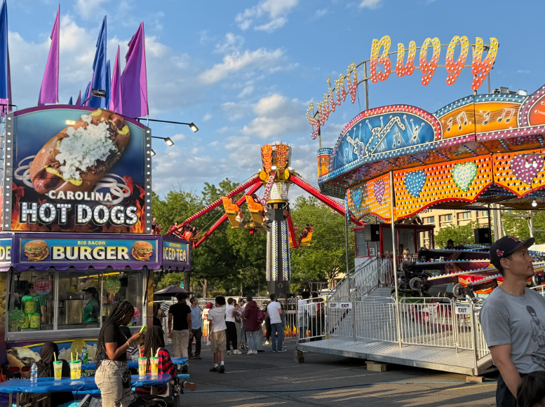 Attendees of the fair walk past various ride and food options on May 10.