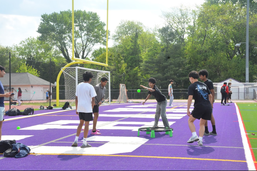 Students play spikeball in one end zone of the football field.