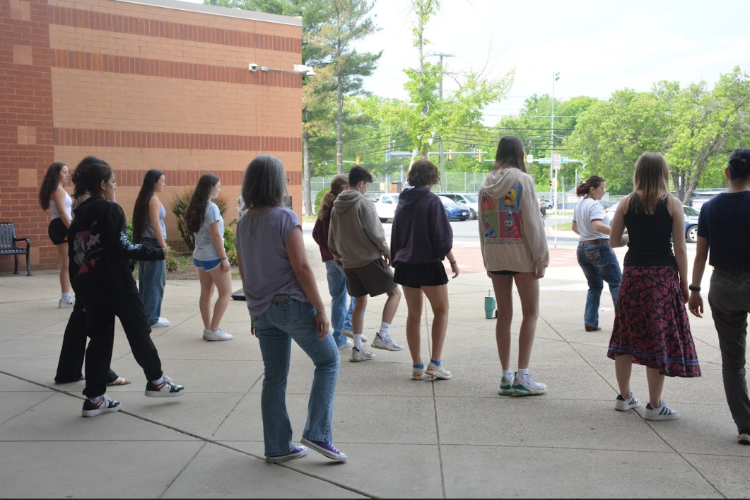 French teacher Elaine Gonzalez demonstrates line dancing steps as students observe and mirror her.