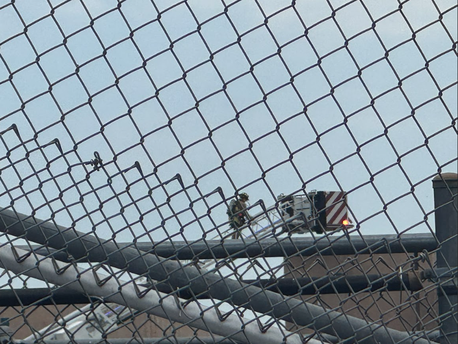 A firefighter climbs up to the school roof via crane.
