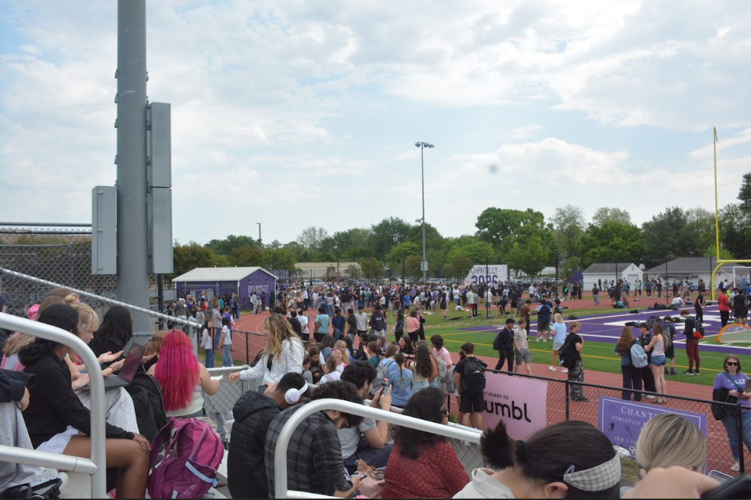Students and staff in the track, field and bleachers wait to be let back inside as fifth period approaches.
