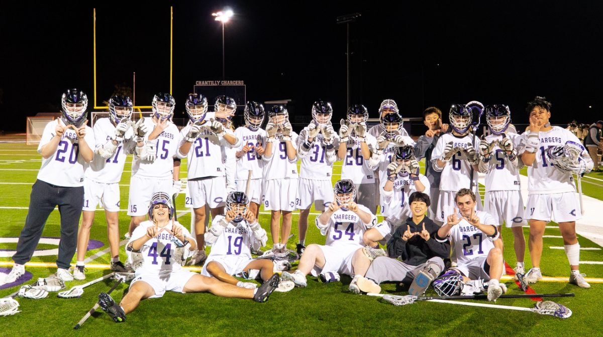The varsity boys lacrosse team huddles together, flashing the winning symbol for a photo on April 20 after winning 9-7 against Westfield High School. Photo used with permission by Ishant Khanal.