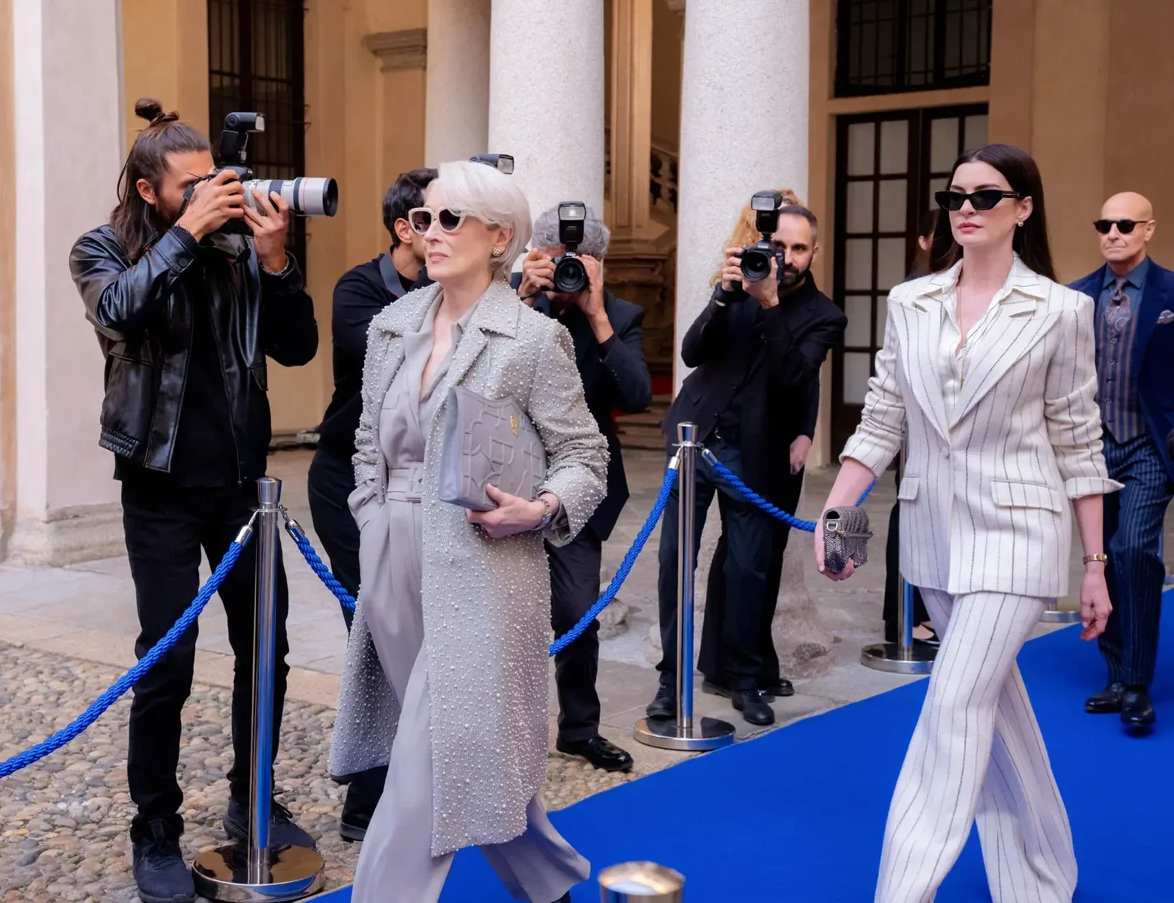 Miranda Priestly (played by Meryl Streep) arrives at the event alongside Andy Sachs (played by Anne Hathaway) as photographers crowd the blue carpet. (Courtesy of Disney)
